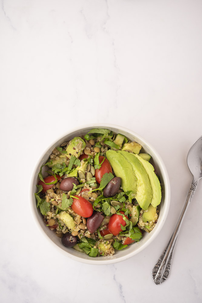 Bovenaanzicht met bakje snelle lunch salade met quinoa en linzen