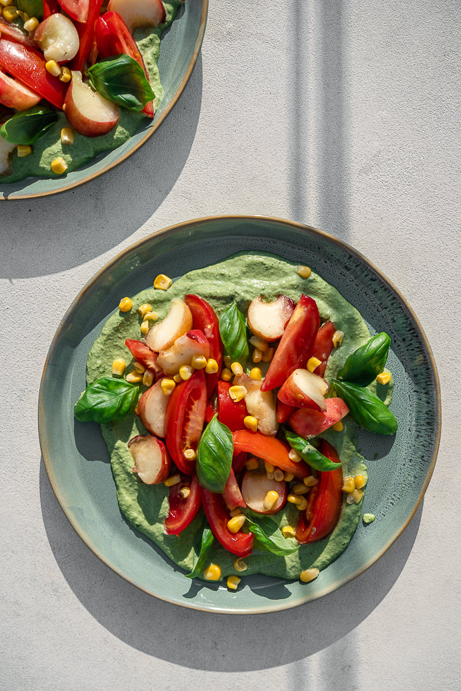 Twee borden met daarop een zomerse salade met tomaat en nectarine. Heerlijk met basilicum dressing.