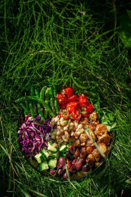 Vegan variant op de klassieke salade niçoise gefotografeerd in hoog groen gras