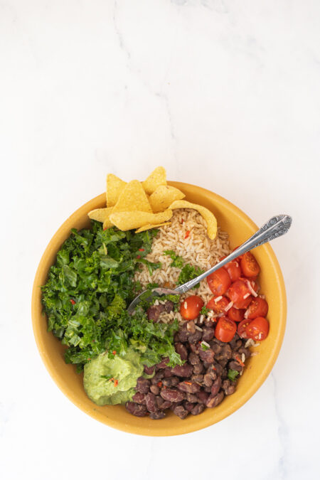 Vegan burrito bowl met boerenkool, avocado, zwarte bonen en tomaat